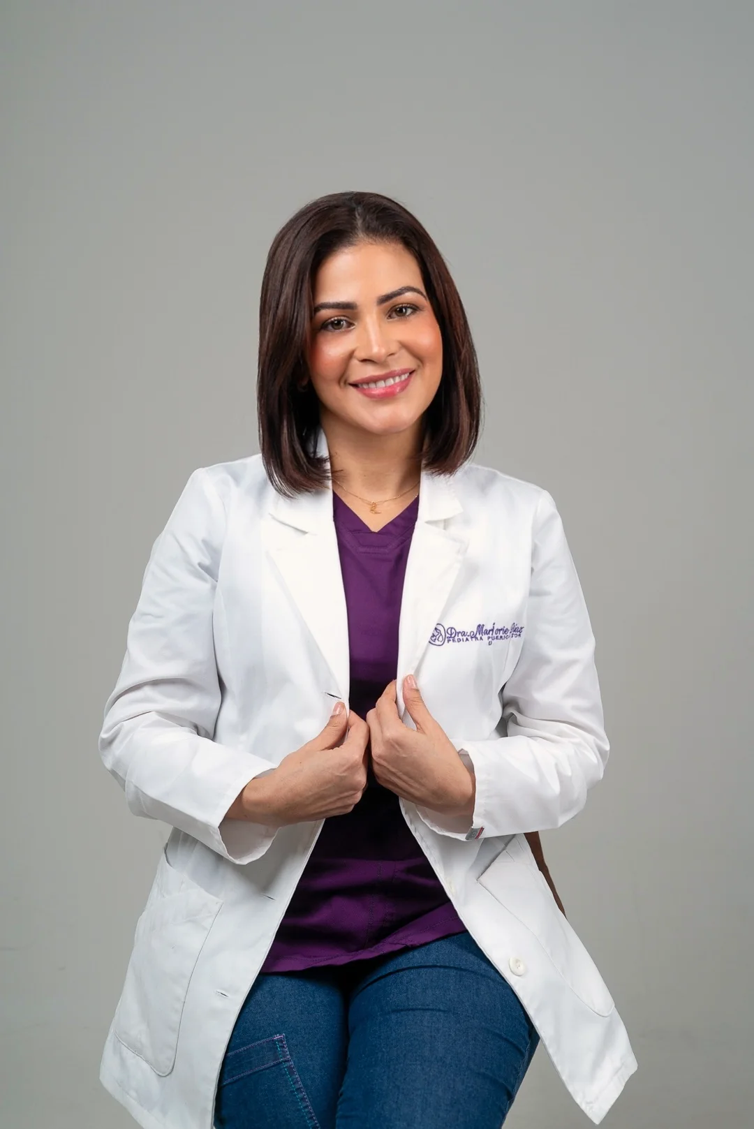 La doctora sonríe con su bata bordada